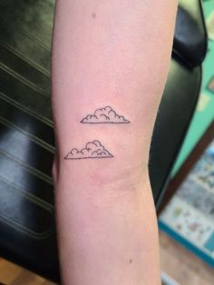 a person with a small tattoo on their arm that has two clouds in the sky