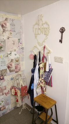 there is a small wooden bench in the corner of this room with many things hanging on the wall