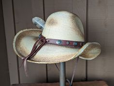 The Cassidy starts with a soft palm hat body that has been flame distressed so it looks like it has already been broken in. The brim is approximately 4" and the crown is 5". There is a wire in the brim so you can shape it however you want. The leather hatband is new rein leather and has lots of Southwestern Conchos. The back of the band has a deer antler bead for accent. Stampede strings are attached to hat which will make it a great hat for riding or on those windy days. Finished with an Owl fe Adjustable High Crown Hat Bands For Country Events, Country Style Festival Hat Bands With High Crown, Custom Mini Hat With Curved Brim For Rodeo, Adjustable Costume Hats With Short Brim For Western Events, Adjustable Distressed Hats For Country Events, Distressed Adjustable Hats For Country Events, Country Style Mini Hat With Curved Brim, Bohemian High Crown Hats For Country Events, Western Costume Hats With Flat Brim For Beach