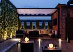 an outdoor living area is lit up at night with lights on the floor and couches