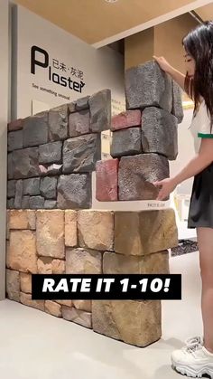 a woman standing next to a pile of rocks in front of a sign that reads rate it 1 - 10