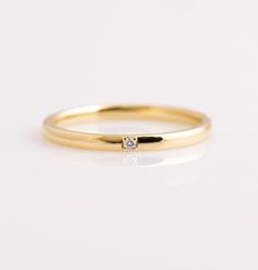 a yellow gold ring with a single diamond in the center, on a white background