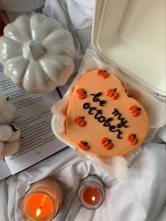 a cake with writing on it sitting next to some candles and pumpkins in the background