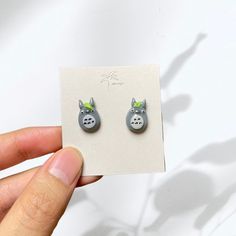 a person holding up a pair of earrings with animals on the front and back of them