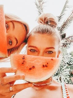 two women holding slices of watermelon in front of their faces