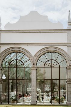 the inside of a building with arched glass doors and windows on both sides, looking into an outdoor dining area