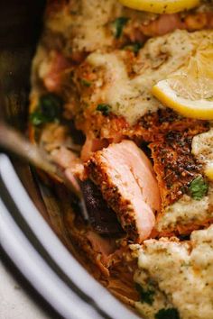 a pan filled with meat and lemons on top of a table next to a fork