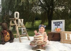 a baby sitting in front of a cake on top of a blanket next to teddy bears