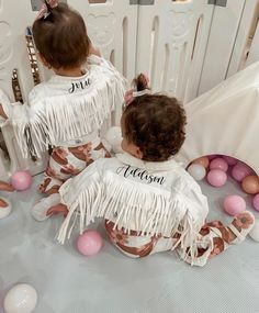 two toddlers dressed in matching outfits sitting on the floor with balloons and decorations around them