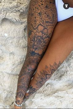 a woman with tattoos on her arm and leg is leaning against a rock face down