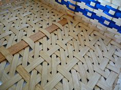 a close up of a woven basket on the floor with blue strips around it and wood sticks sticking out