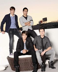 three young men sitting on top of a wicker basket