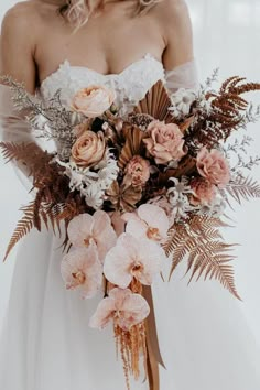 a woman holding a bouquet of flowers in her hands and wearing a wedding dress with long sleeves