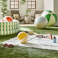 several beach balls are laying on the grass in an open room with chairs and tables