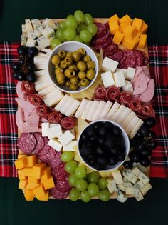 an assortment of cheeses, meats and olives are arranged on a platter