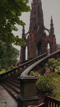 an old building with stairs leading up to it and flowers growing on the ground below