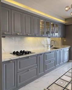 a kitchen with gray cabinets and marble counter tops, along with white tile flooring