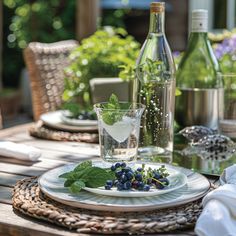 a table set with plates, glasses and bottles of wine in the back yard area