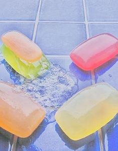 three popsicles sitting on top of a blue tiled floor next to water and ice