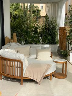 a living room filled with lots of furniture next to a tree covered patio area in front of a building