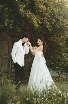 a bride and groom standing in front of some trees