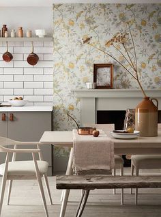 a table with two chairs and a vase on top of it next to a fireplace