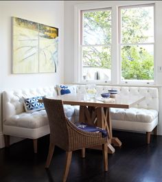 a white couch sitting next to a wooden table in a living room under a window