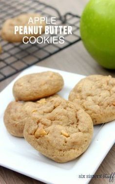 three cookies sitting on top of a white plate next to an apple and cooling rack