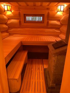 the inside of a wooden cabin with benches and lights on it's windows are lit up