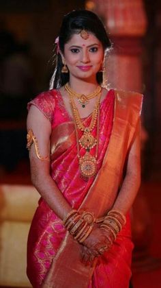 a woman in a red and gold saree standing with her hands on her hips