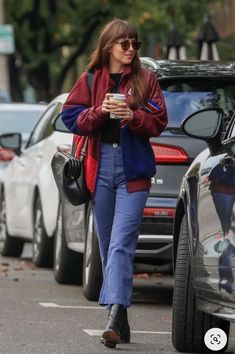 a woman walking down the street while holding a cup