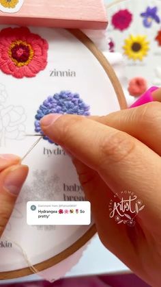 a person is stitching flowers on a cross - stitch pattern with a needle and thread