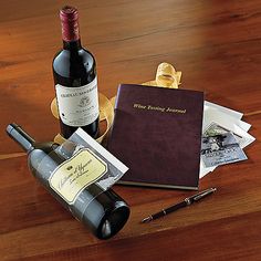 two bottles of wine sitting on top of a wooden table next to a notepad and pen