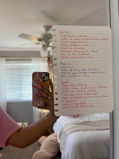 a woman taking a selfie in front of a bedroom mirror with writing on it