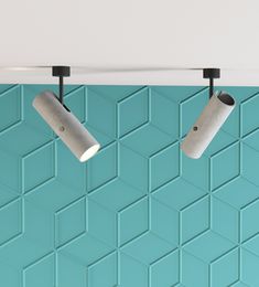 two lamps are hanging from the ceiling in front of a blue wall with geometric tiles