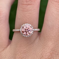 a woman's hand with a pink diamond ring on top of her wedding band