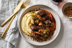 a white plate topped with mashed potatoes and meat next to a glass of wine