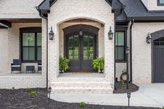 a white brick house with black doors and windows