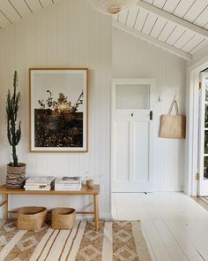 a living room with white walls and wood flooring on the floor, along with a wooden bench