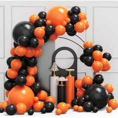 an orange and black balloon arch is surrounded by balloons