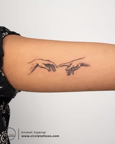 two hands touching each other with one hand holding the other's finger tattoo on the right arm