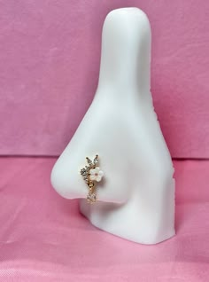 a white mannequin head with a ring on it's side and a pink background