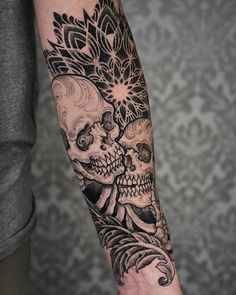 a man's arm with a skull and flower tattoo on the left side of his arm