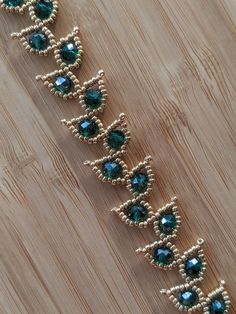 a gold and green beaded bracelet on a wooden surface