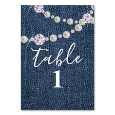 a table number card with pearls on denim fabric and the word table 1 in white