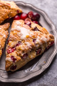 two slices of cranberry scones on a plate with cherries and cream