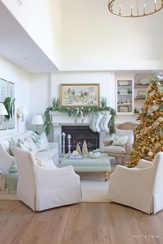 a living room filled with white furniture and a christmas tree in the middle of it