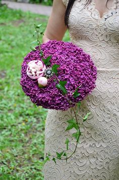 a woman in a white dress holding a purple flower bouquet