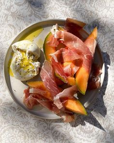 a white plate topped with sliced fruit and an egg on top of it next to other food items