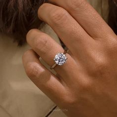 a woman's hand with a diamond ring on her left hand, showing the center stone